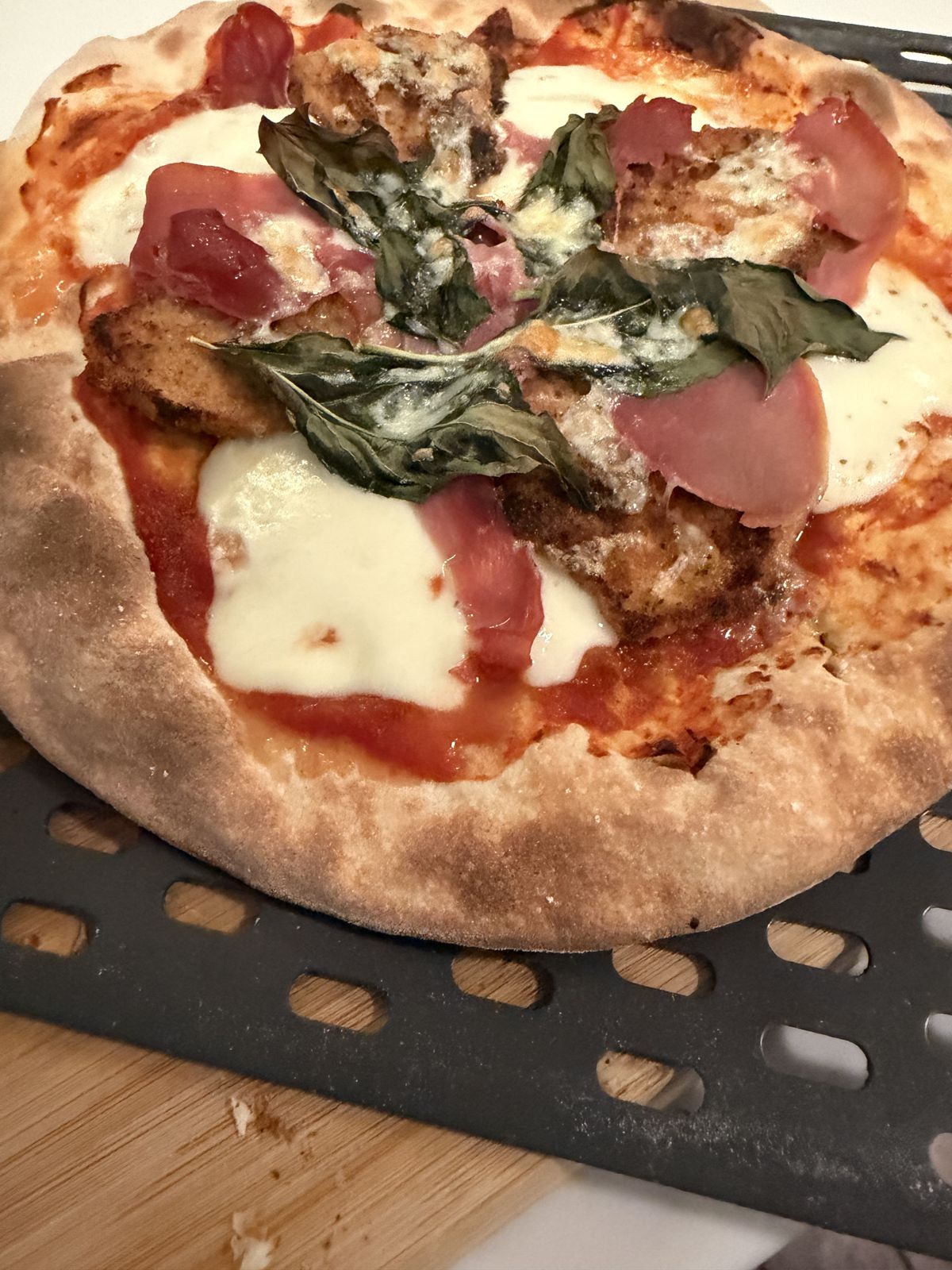 Finished pizza with breaded eggplant, prosciutto, fresh mozzarella, and basil on the Ninja perforated peel