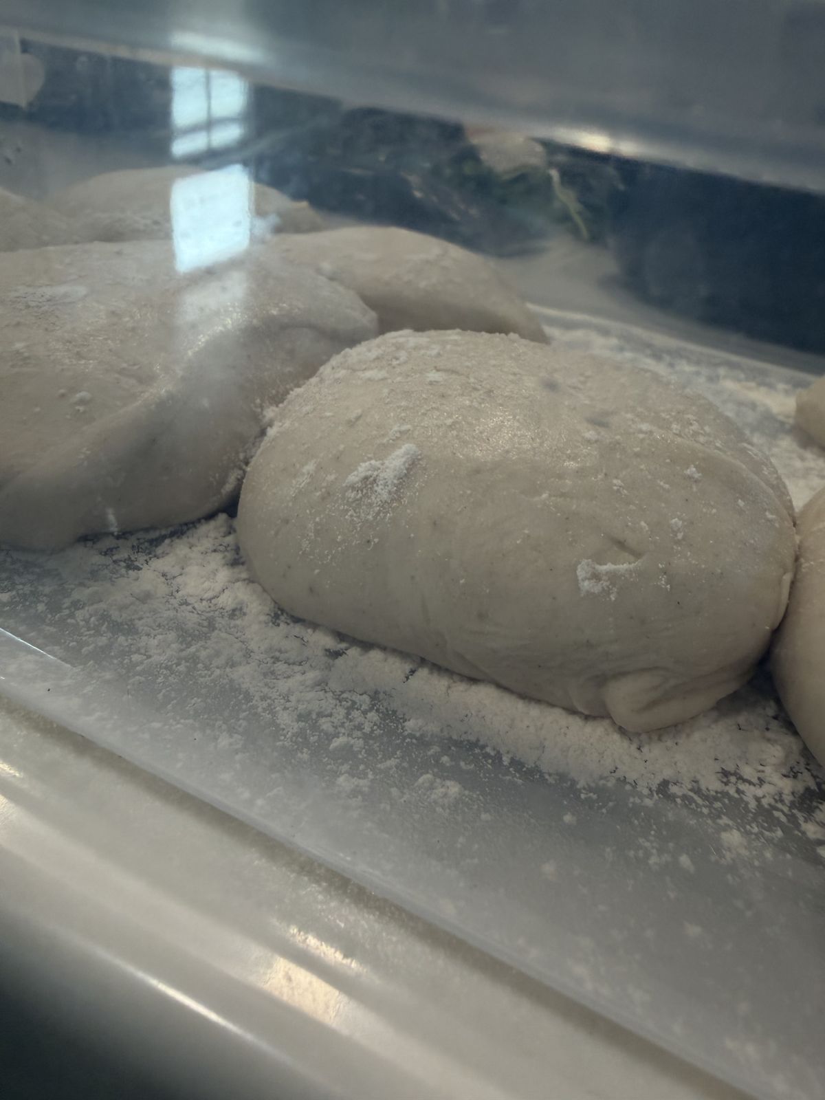 Close-up of dough balls resting on the floured floor of a proofing tray