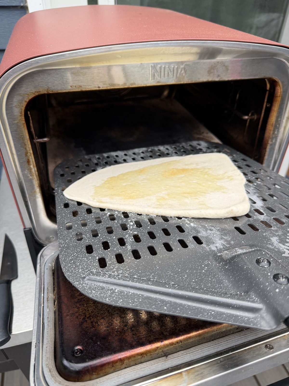 Spreading fresh pesto across the stretched dough