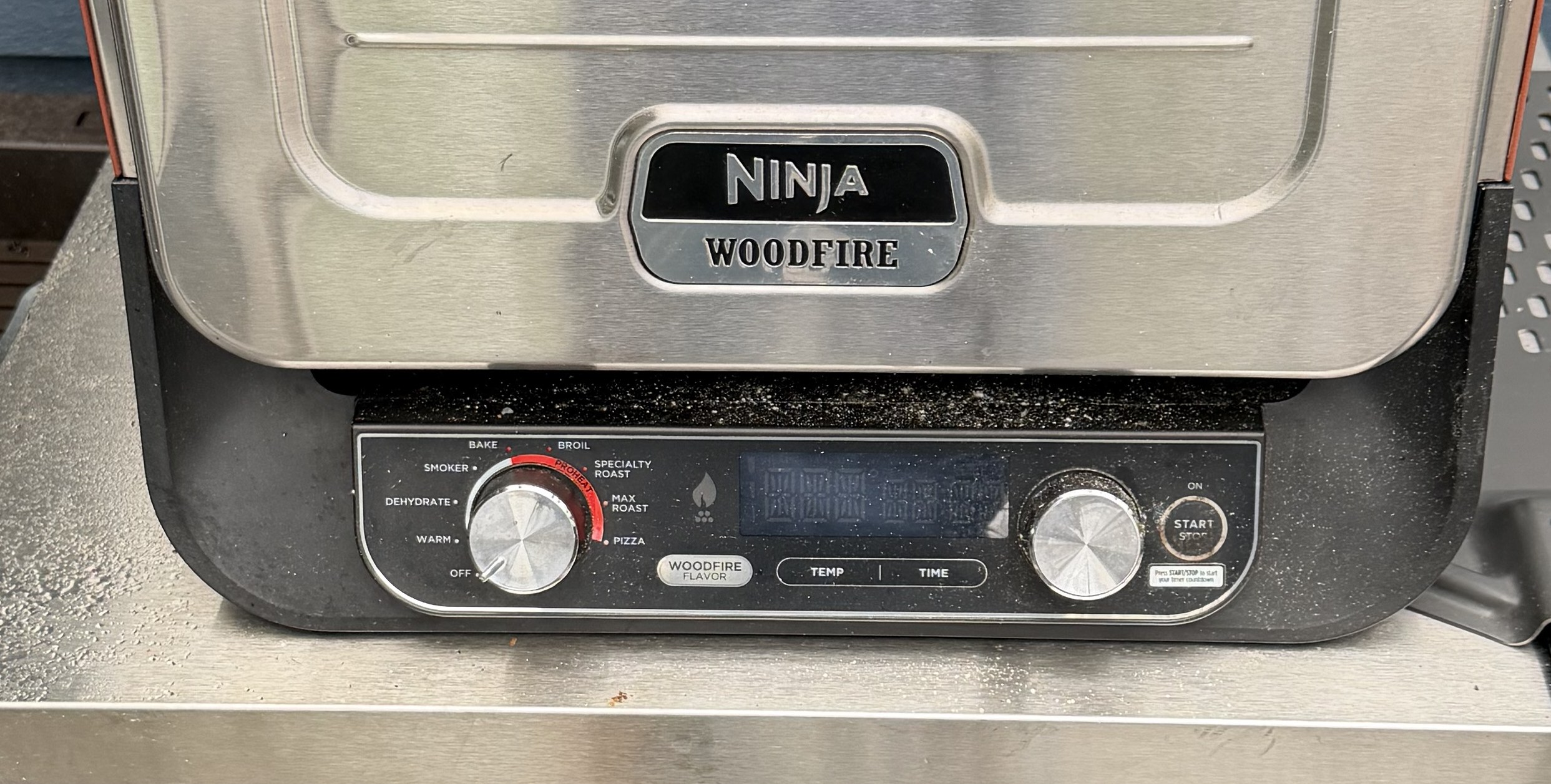 The front of a Ninja Woodfire Pizza Oven — the NINJA WOODFIRE badge above the control panel